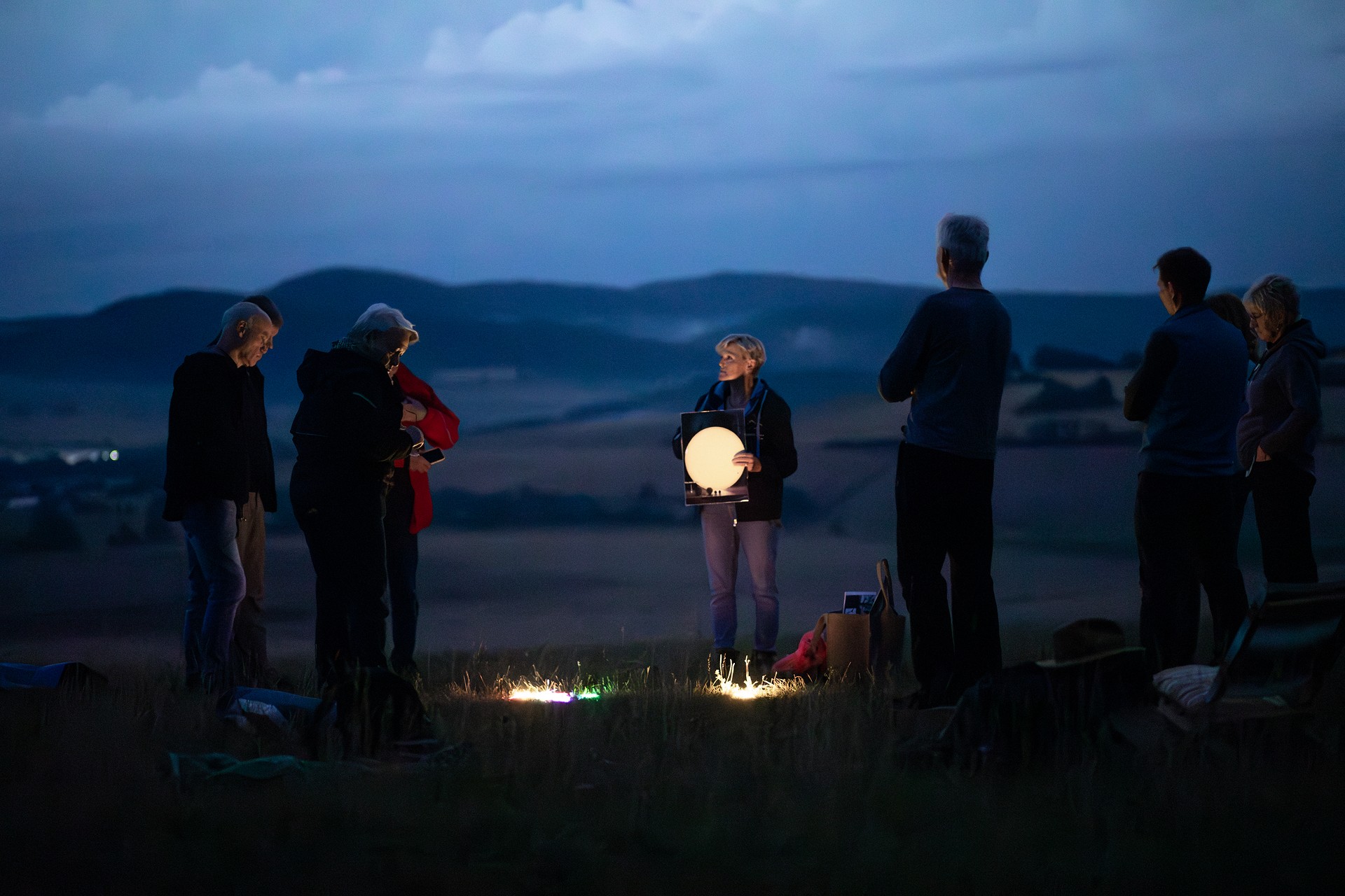 Personengruppe bei einer Sternenparkführung. Die Sternenparkführerin hält einen leuchtenden Mond.