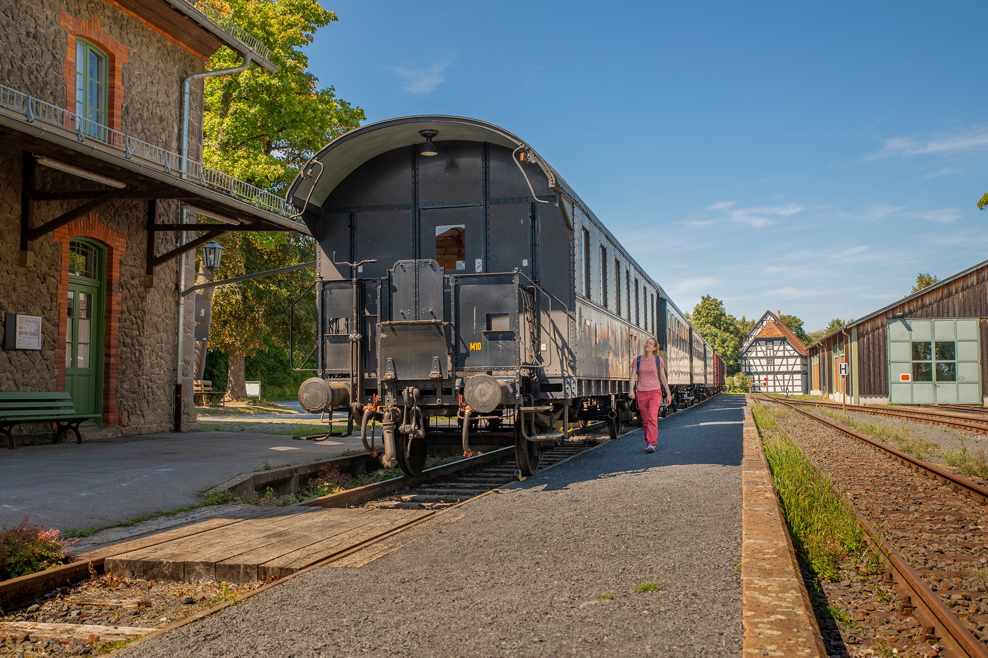 Wandeirn läuft neben einem alten Zugwagon eines Güterzuges.