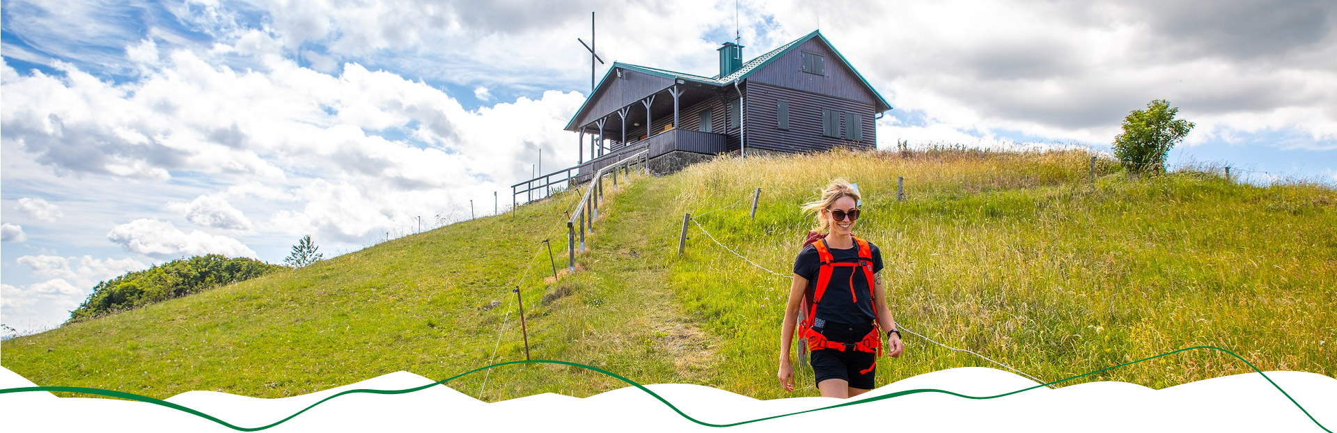 Wanderin läuft einen Weg herunter. Im Hintegrund ist die Dermbacher Hütte.