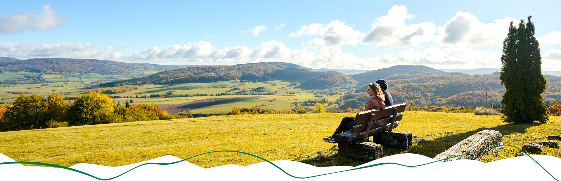 Wanderpaar sitzt auf einer Bank und blickt in die Ferne der Rhön.