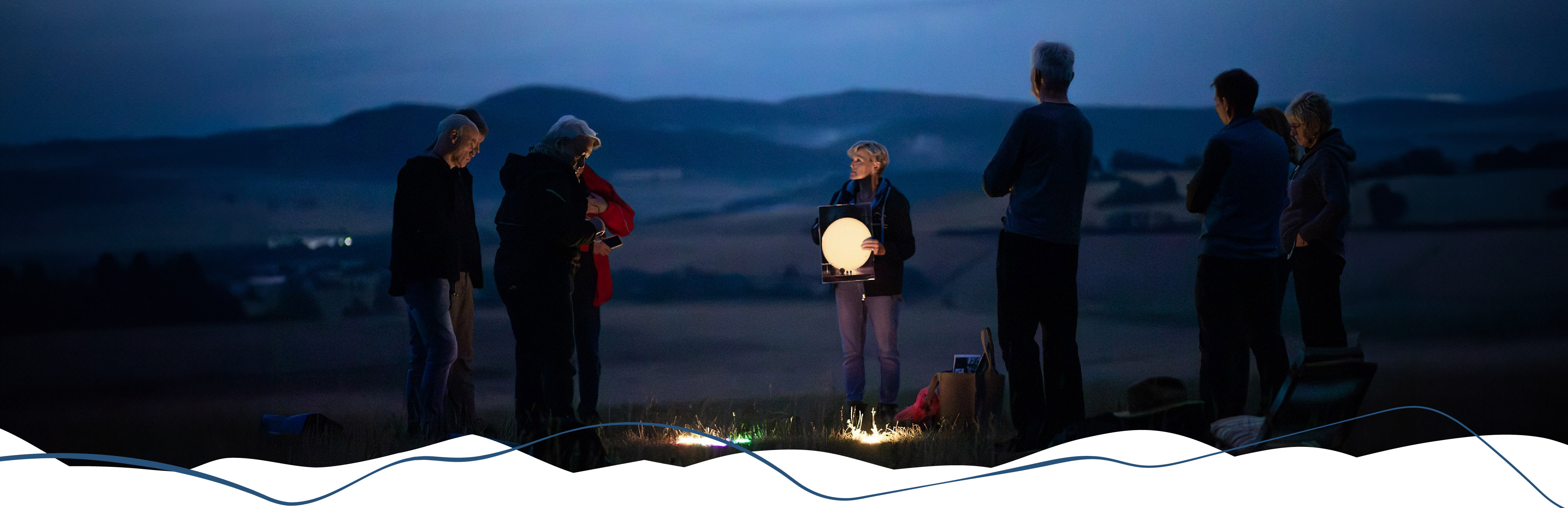 Personen bei einer Sternenparkführung in der Rhön. Die Erzählerin hält einen leuchtenden Mond in der Hand.