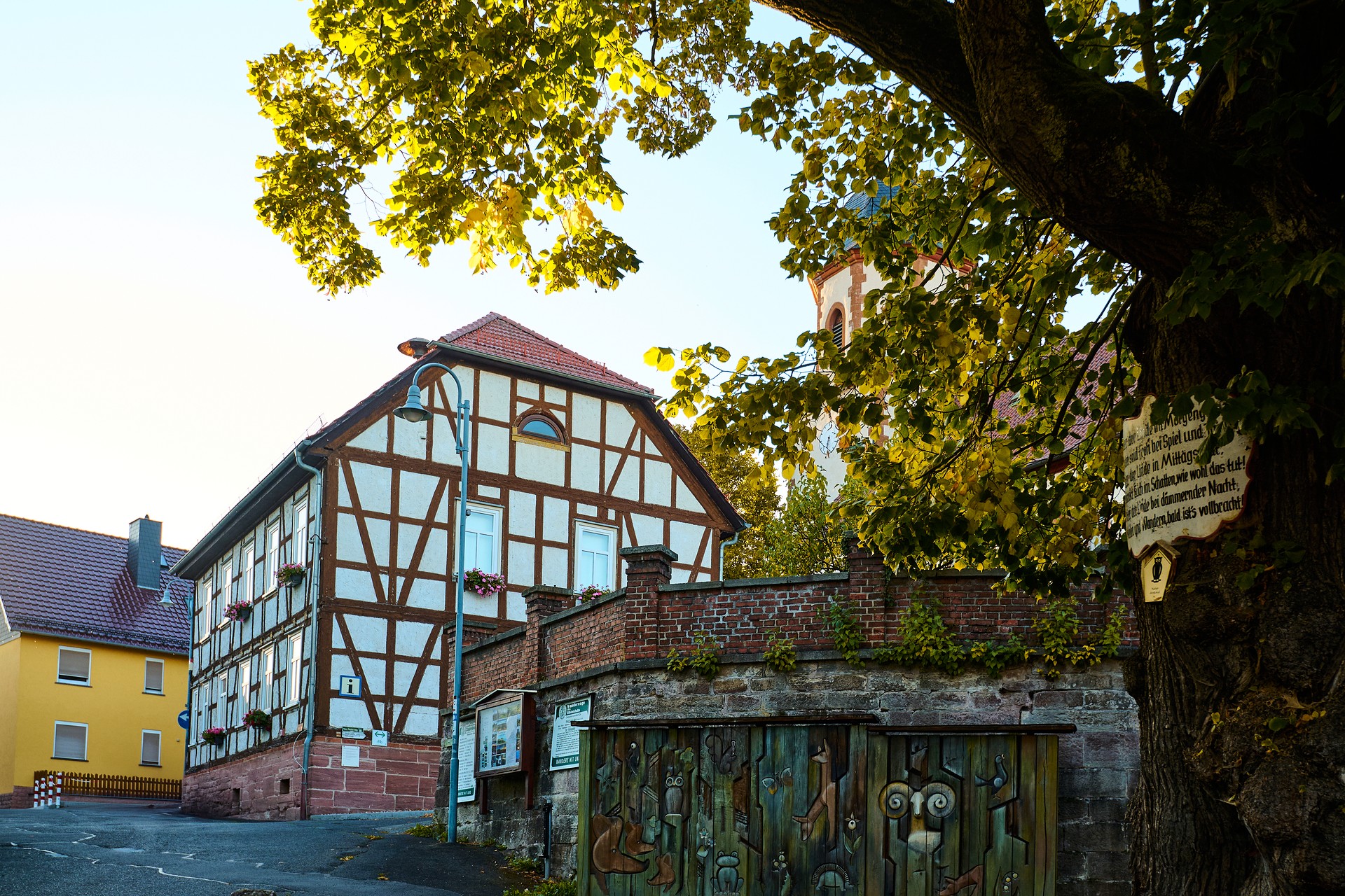 Altes Fachwerk Haus mit Mauer, die künsterlisch bemalt ist.