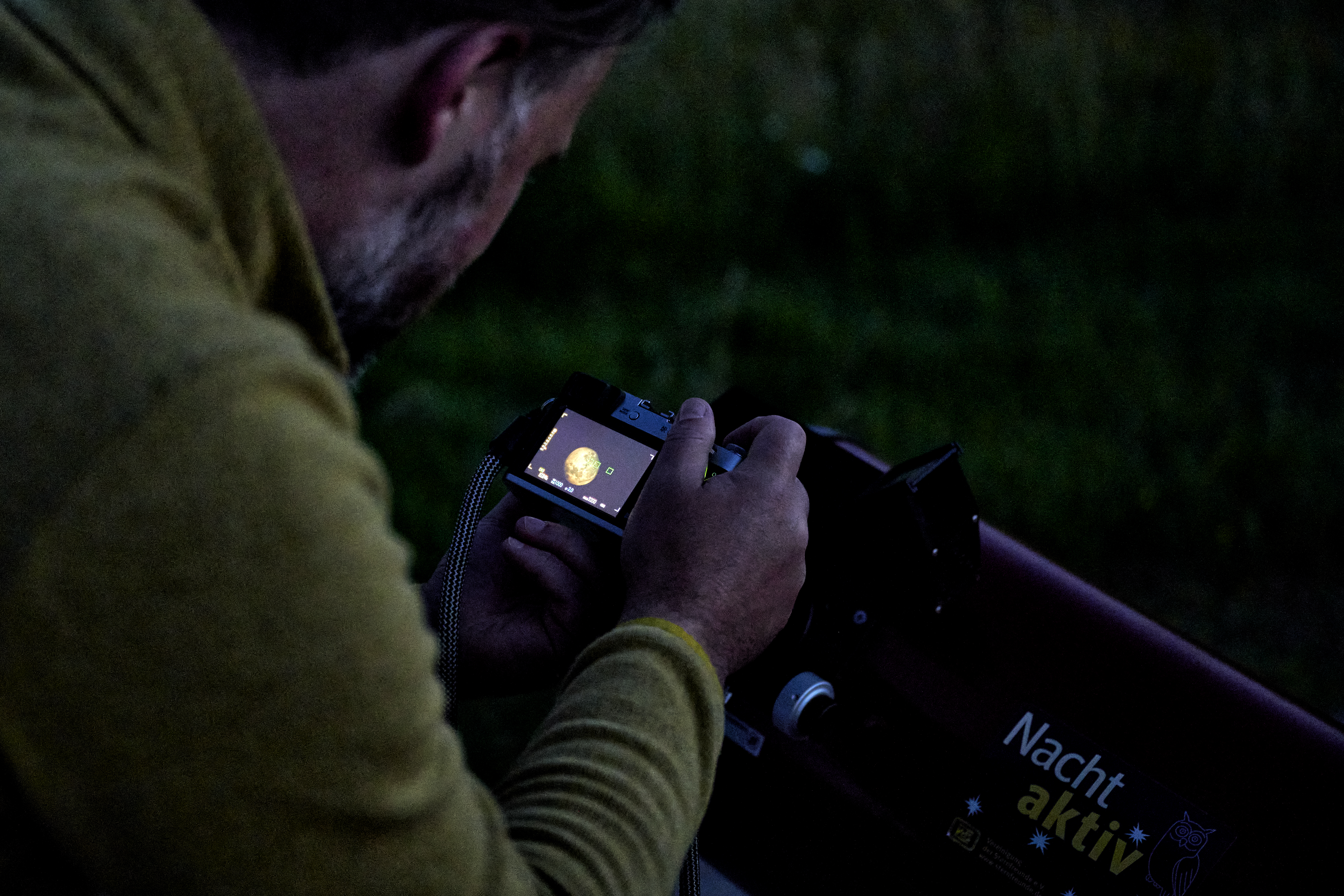 Person fotografiert den Mond durch ein Teleskop.
